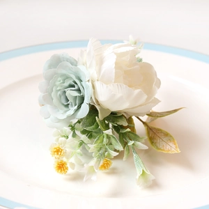 Detailansicht eines Serviettenrings mit künstlicher weißer Pfingstrose und blauer Rose