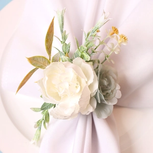 Makro-Detail des Serviettenrings mit weißer Rose und grünen Blättern auf Leinen