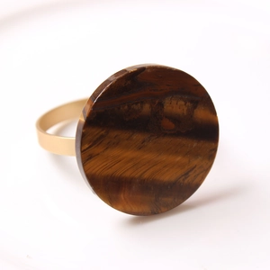 Macro shot of tiger eye stone ring with brown stripes and wide golden band finish