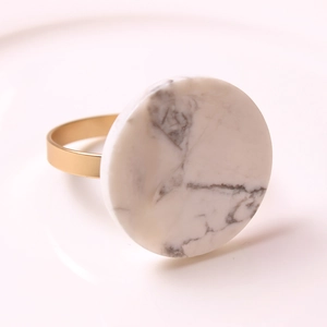 Macro shot of matte gold napkin ring featuring a round white marble stone inlay