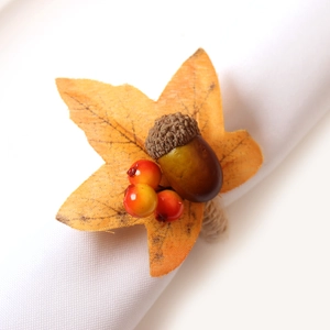 Autumn napkin ring with orange maple leaf, brown acorn and berries on white linen