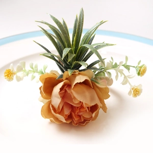 DIY rose fabric flower napkin ring with coral peonies and green leaves on a white plate