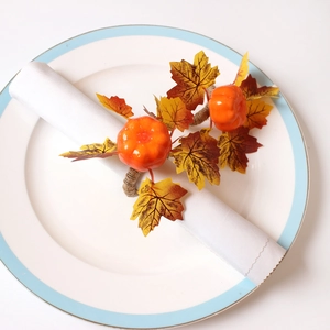 Kürbis- und Ahornblatt-Serviettenringe auf weißem Teller für herbstliche Tischdeko