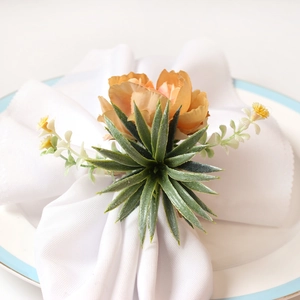 Detail of an orange silk rose napkin ring with green leaves and white accent flowers