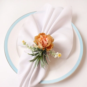 Close-up of elegant orange fabric rose napkin ring on a white ceramic dining plate
