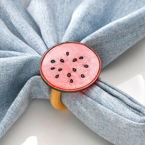 Wooden watermelon napkin ring with red fruit slice detail on a light blue napkin