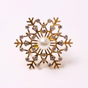 Golden snowflake napkin ring with central pearl and white rhinestones on white background
