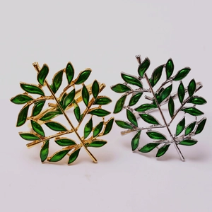 Set of gold and silver Christmas tree leaf napkin rings with green enamel details