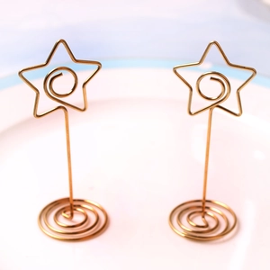 Golden star-shaped metal card holders with spiral base for weddings and events