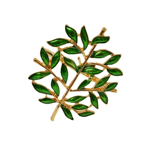 Golden Christmas tree napkin ring with vibrant green enamel leaves on a white background