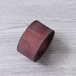 Close-up of deep red wooden napkin ring showing smooth polished natural grain texture