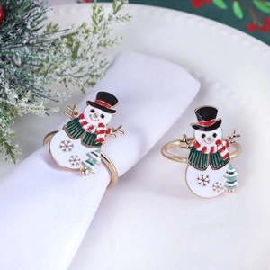 Detail shot of golden metal snowman napkin rings with colorful enamel on white napkin