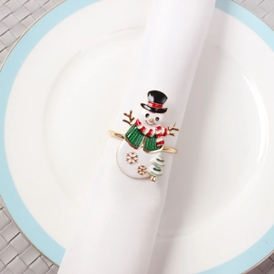 Detail of enamel snowman napkin ring with gold snowflakes on white cloth napkin