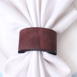 Minimalist brown wood napkin ring with natural grain on a white cloth napkin