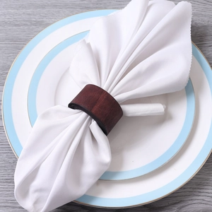 Detail of dark brown wooden napkin ring with natural grain on a white linen napkin