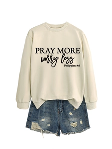 Flat lay of beige sweatshirt with Pray More Worry Less print and frayed denim shorts