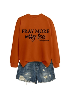 Detailed flat lay of orange sweatshirt with Pray More Worry Less print and denim shorts