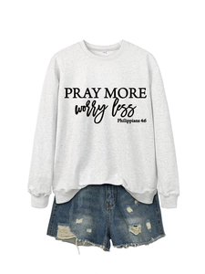 Detail shot of Pray More Worry Less typography on gray crewneck sweatshirt with denim shorts