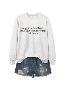Detail of grey crewneck sweatshirt with black text and ripped denim shorts set