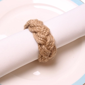 Macro shot of handmade braided hemp rope napkin ring on white fabric napkin detail
