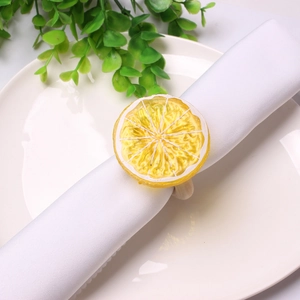 Dettaglio dell'anello portatovagliolo con limone artificiale e trama gialla su tovagliolo