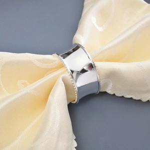 Elegant silver alloy napkin ring with beaded edges on yellow fabric backdrop