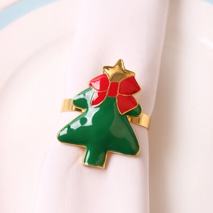 Close-up of golden metal Christmas tree napkin ring with red bow and green enamel