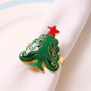 Close-up of green enamel Christmas tree napkin ring with red star on white cloth