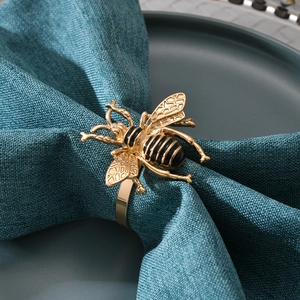 Servilletero de abeja dorada con esmalte negro sobre servilleta de tela azul