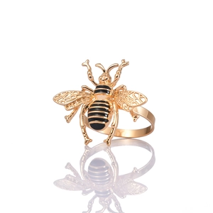 Servilletero de abeja dorada con alas caladas y rayas de esmalte sobre un fondo blanco