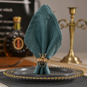 Servilletero de abeja dorada con alas vintage sobre tela de lino verde oscuro