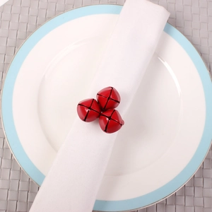Lot de ronds de serviette cloches de Noël rouges sur serviette en lin blanc élégante