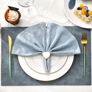 Rose gold heart-shaped napkin ring with blue linen napkin on a luxury table setting