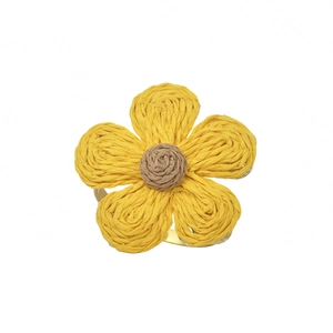 Handcrafted raffia plum blossom napkin ring with golden metal base on white background