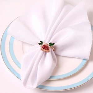 Détail d'un rond de serviette doré avec cloches émaillées rouges et feuilles de houx