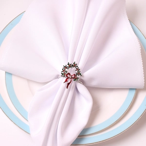 Détail du rond de serviette en forme de houx de Noël avec nœud rouge et baies