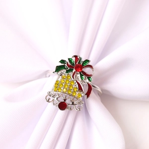 Détail d'un rond de serviette cloche de Noël avec nœud rouge et strass jaunes