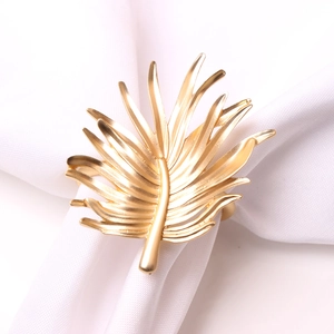 Golden palm leaf metal napkin ring with detailed vein texture for elegant table settings