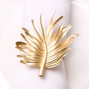 Elegant gold palm leaf napkin ring with metal texture on white fabric for hotel decor