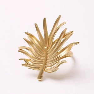 Golden palm leaf metal napkin ring with textured leaf veins on a white background