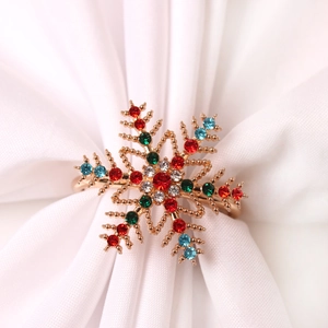 Détail du rond de serviette flocon de neige avec strass colorés sur tissu blanc