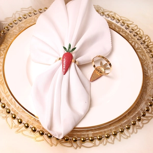 Close-up of a glossy red carrot napkin ring with gold metal band on a dinner plate