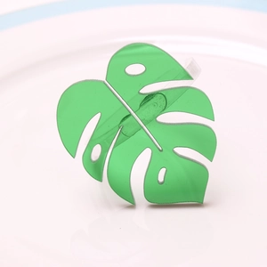 Green acrylic monstera leaf napkin ring displayed on a minimalist white ceramic tray