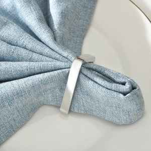 Modern silver rectangle metal napkin ring with polished finish on blue linen napkin
