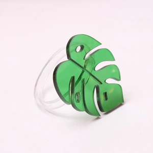 Macro detail of a green acrylic monstera leaf napkin ring with clear textured veins