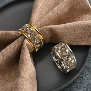 Detalle de servilleteros de lujo con pedrería en oro y plata sobre una mesa elegante