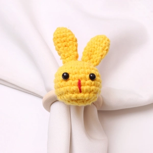 Close-up of handmade yellow crochet bunny napkin ring with natural wooden loop detail