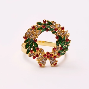 Close-up of golden Christmas wreath napkin ring with green leaves and red rhinestones