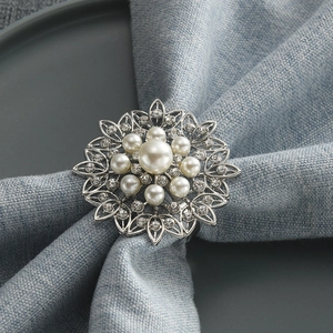 Floral silver metal napkin ring with pearl and rhinestones on light blue fabric