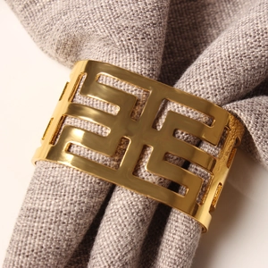 Golden hollow geometric metal napkin ring on a premium grey linen cloth napkin